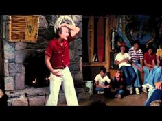 the young boy is wearing a cowboy hat and white pants while standing in front of a group of people