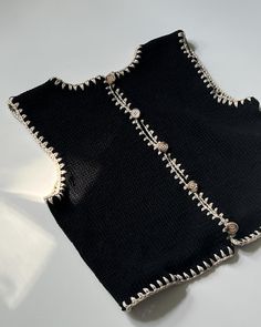 two pieces of black cloth with silver beads on them sitting next to each other in front of a white background