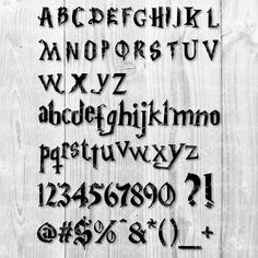 an old fashioned font and numbers on a wooden background with the letters written in black ink