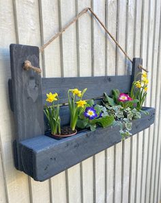 a wooden shelf with flowers and plants hanging from it