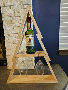 a wine glass holder with two glasses on it and a bottle in front of a fireplace