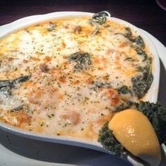 a white plate topped with a casserole covered in cheese and broccoli