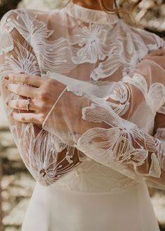 a woman wearing a white wedding dress and holding her hands in her pocket with the sleeves open