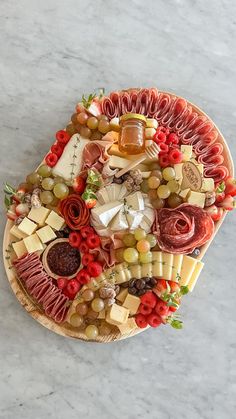 a platter filled with meats, cheeses and other foods on a marble surface