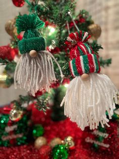 two christmas ornaments hanging from the top of a tree in red, green and gold tinsel