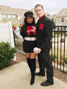 a man and woman dressed up in costumes standing next to each other near a fence