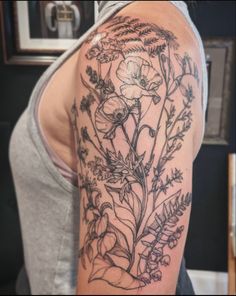 a woman's arm with flowers and leaves tattooed on the back of her shoulder