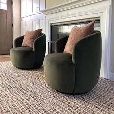 two green chairs sitting on top of a rug next to a fire place in a living room