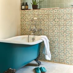 a blue bath tub sitting next to a tiled wall