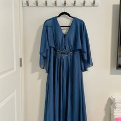 a blue dress hanging on a coat rack next to a white door with a mirror