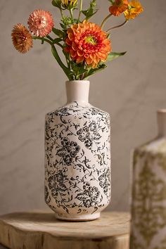 a white vase with flowers in it sitting on a table next to two vases