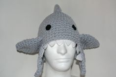 a white mannequin head wearing a crocheted hat with a shark on it