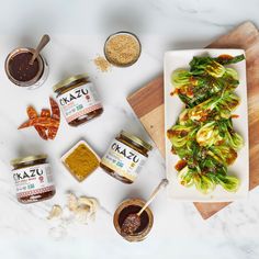 some food is laying out on a cutting board and next to it are jars of sauces