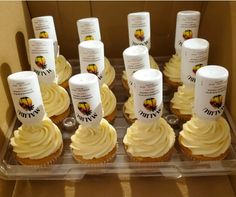 cupcakes with white frosting are arranged in a display case on a table