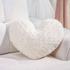 a heart shaped pillow sitting on top of a white couch