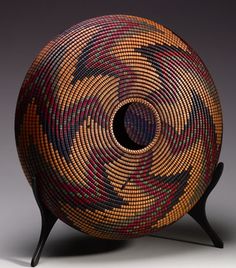 a woven basket sitting on top of a wooden stand in front of a gray background