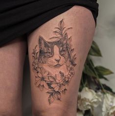 a woman's thigh with a cat and flowers tattoo on the side of her leg