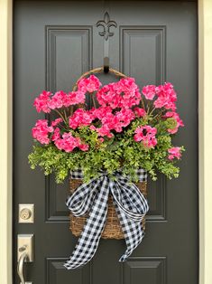 pink flowers in a basket hanging on the front door with a gingham bow