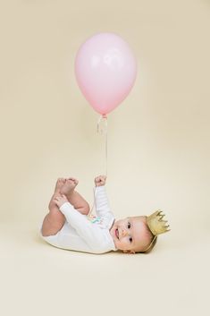 a baby laying on its back holding a balloon