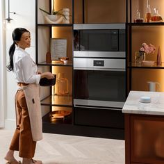 a woman standing in front of a microwave oven