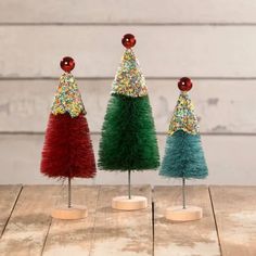 three small christmas trees with colorful decorations on them