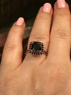 a close up of a person's hand with a black diamond ring on it