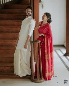 a man and woman standing next to each other in front of a stair case holding hands