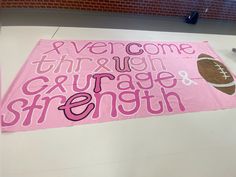 a pink banner that says, everyone through courage and strength with a football on it