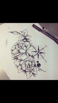 a drawing of flowers on paper with a compass in the middle and an ink pen next to it