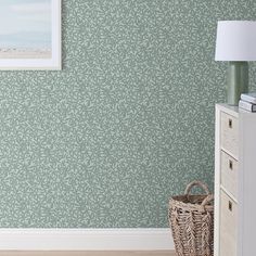 a room with green wallpaper and a basket on the floor next to a lamp