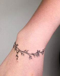 a woman's arm with a small branch tattoo on it