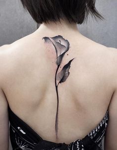 the back of a woman's neck with a black and white flower tattoo on it