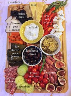 a platter with different types of meats and cheeses, including olives, tomatoes, peppers, mushrooms, pita bread