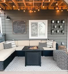 an outdoor living area with couches, tables and lights on the outside patio wall