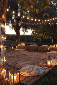 candles are lit on the ground in front of hay bales with lights strung from them