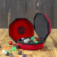 a red case filled with dice sitting on top of a wooden table next to other dice