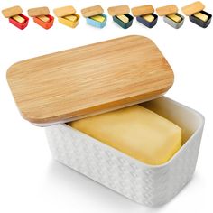 a wooden cutting board in a white container with four different colored cheese cubes next to it