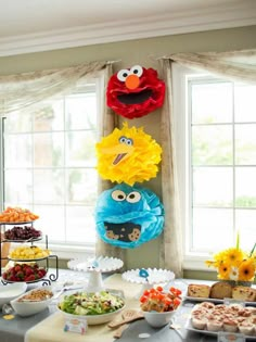 an assortment of food on a table with sesame street characters hanging from the wall behind it