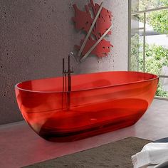 a red bath tub sitting on top of a bathroom floor next to a large window