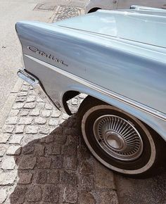 an old car is parked on the side of the road in front of another car