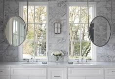 a bathroom with marble walls and two mirrors on the wall, along with double sinks