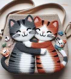 a crocheted purse with two cats hugging each other on the front and side