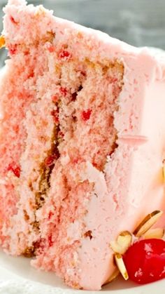 a piece of cake with white frosting and cherries on the top is sitting on a plate