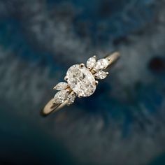 an engagement ring with three pear shaped diamonds on it's side, in front of a blue background