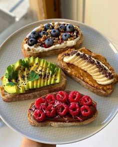 there are four different types of breads on the plate with berries, bananas and kiwi