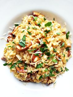 a white plate topped with pasta and meat covered in parmesan cheese, garnished with fresh herbs