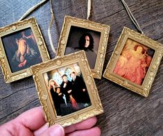 hand holding three small framed pictures in front of a wooden table with string attached to it