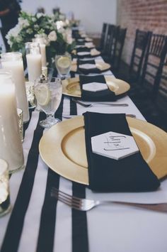 the table is set with black and white striped linens, gold place settings, candles, and napkins