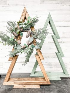 a wooden christmas tree with pine cones and greenery in the shape of a triangle