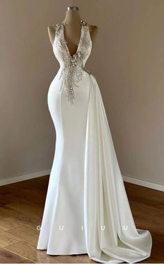 a white wedding dress with an open back and beaded detailing on the neckline